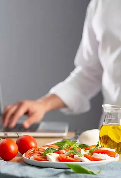 Вертикальный кадр салата, сыра, ноутбук и руки модели