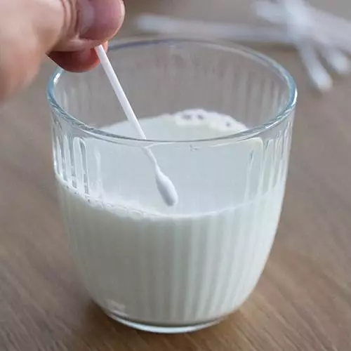 Ватные палочки для очистки капли молока в стакане